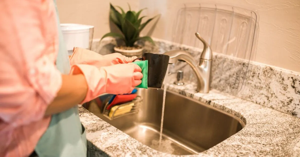 Hand inspecting kitchen sink garbage disposal for clogs